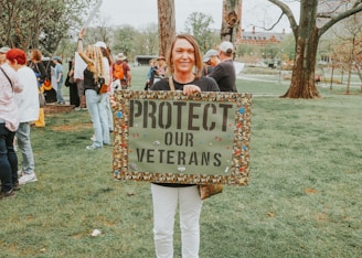 Woman protests to protect veterans with sign.