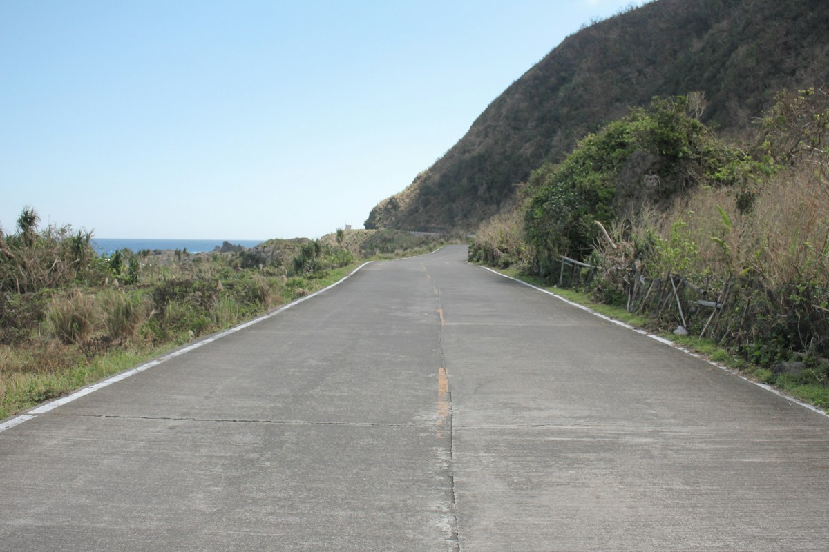 一條筆直的公路通往海邊，象徵台灣自駕旅程的自由與開闊