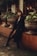 Woman in black coat poses outdoors by flowerpots.