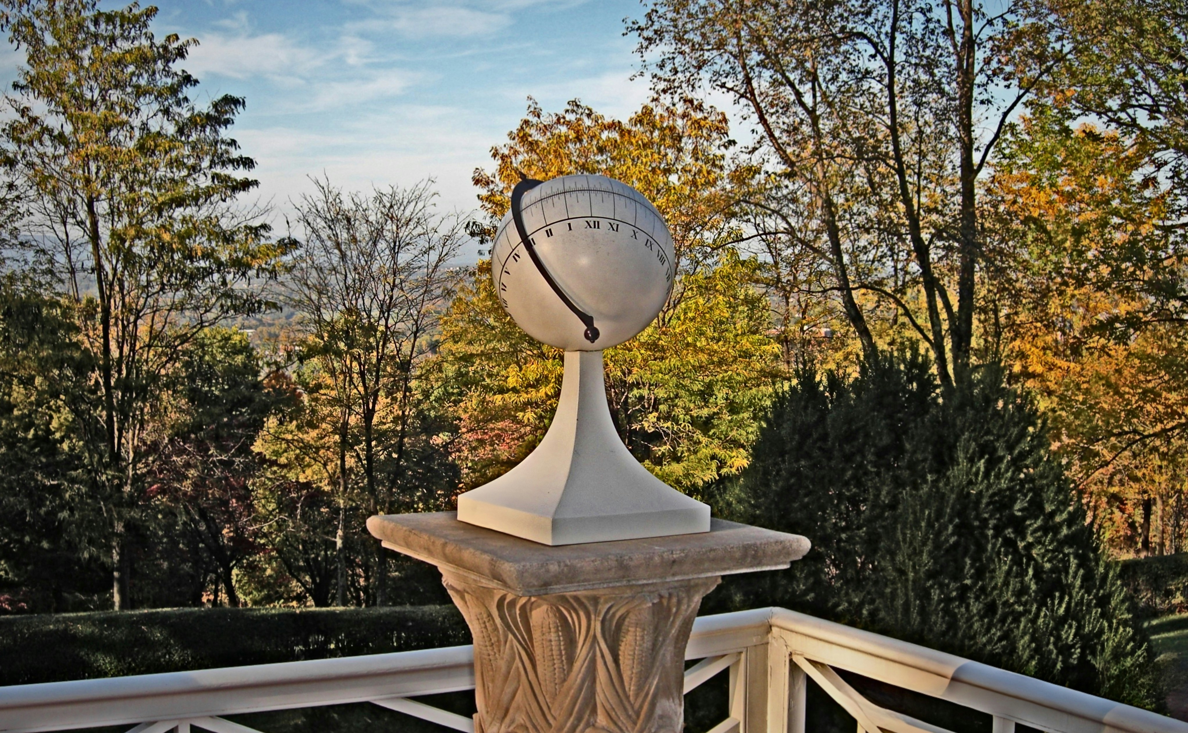 A globe sits atop a pillar outdoors.
