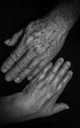 Une main d'adulte à côté d'une main d'une personne âgée