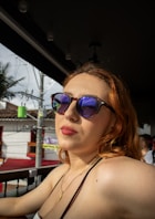 A woman wearing sunglasses looks off to the side.