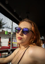 A woman wearing sunglasses looks off to the side.