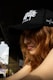 A woman with red hair wears a black hat.