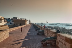 A long wall overlooks the ocean and the city.