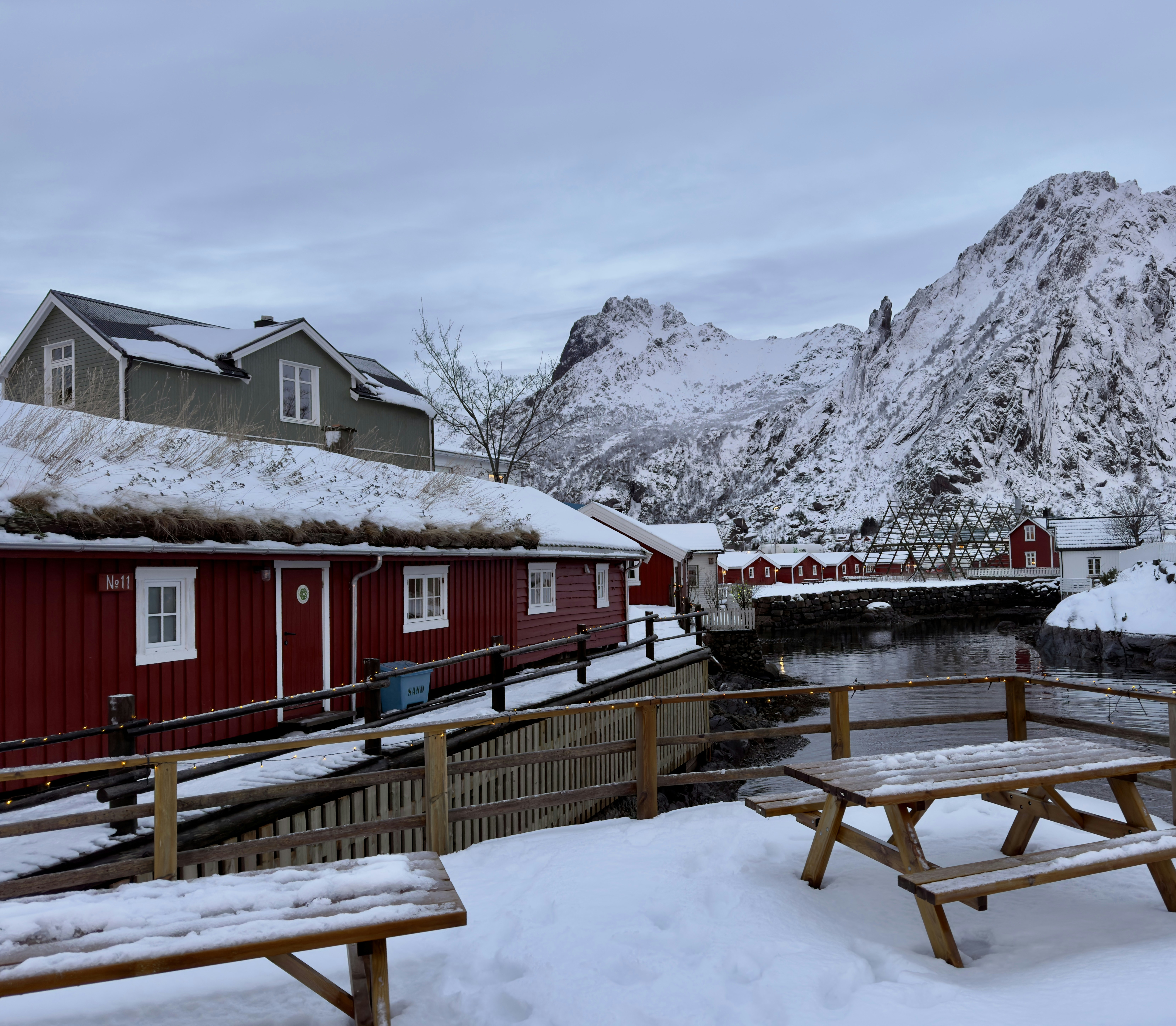 Snowy village scene with red buildings and mountains.