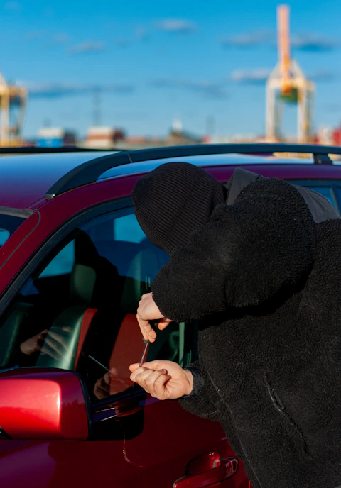 A thief is trying to break into a car