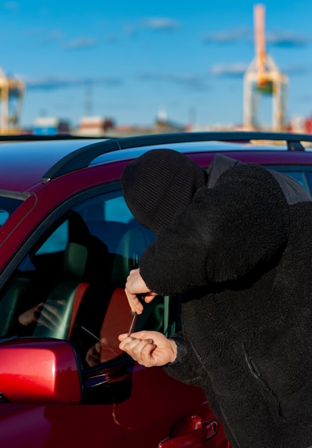 Pessoa tentando arrombar um carro a noite, ilustrando fraude de seguro com falso roubo de veiculo