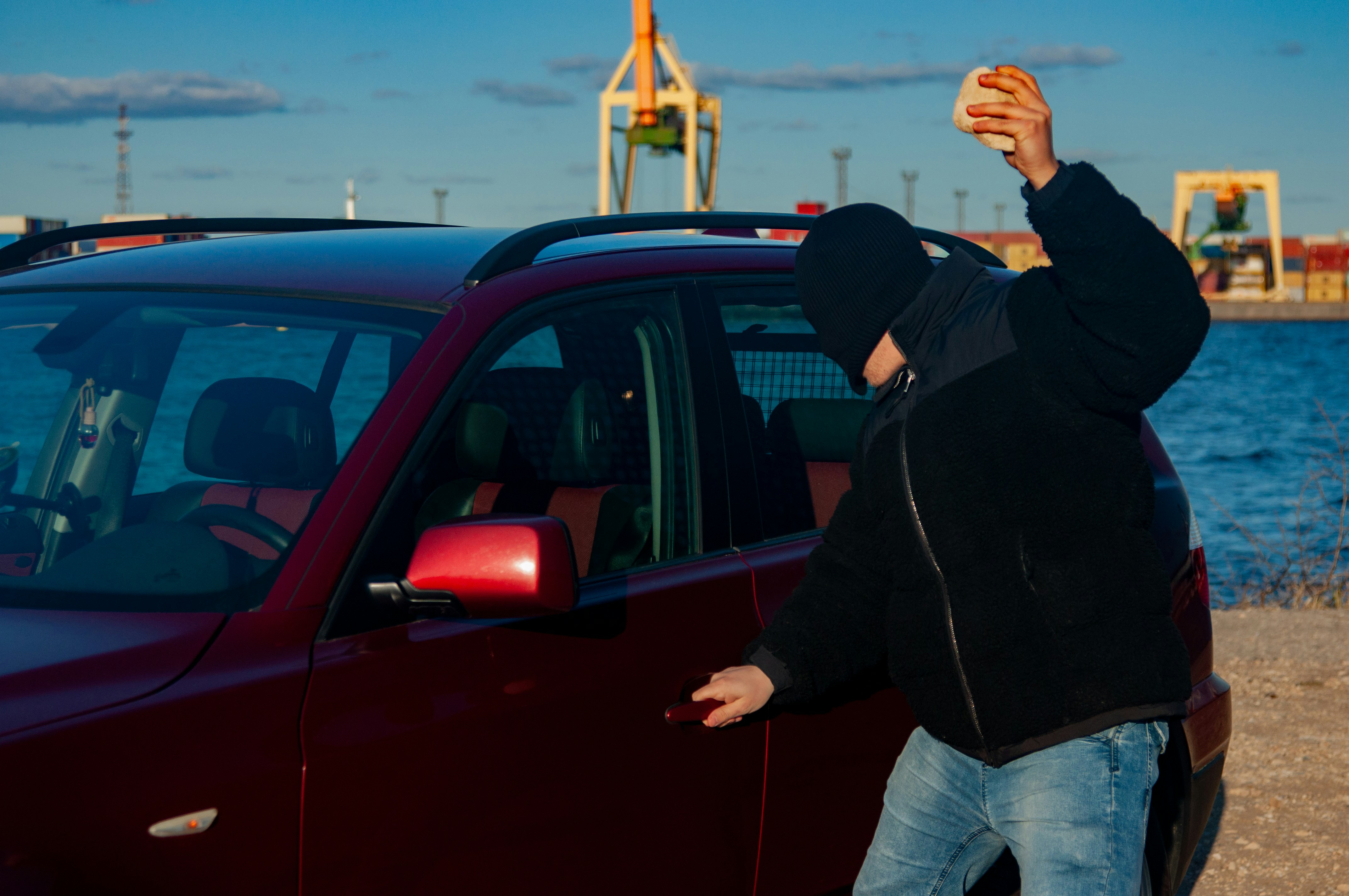 A masked person attempts to break into a car.