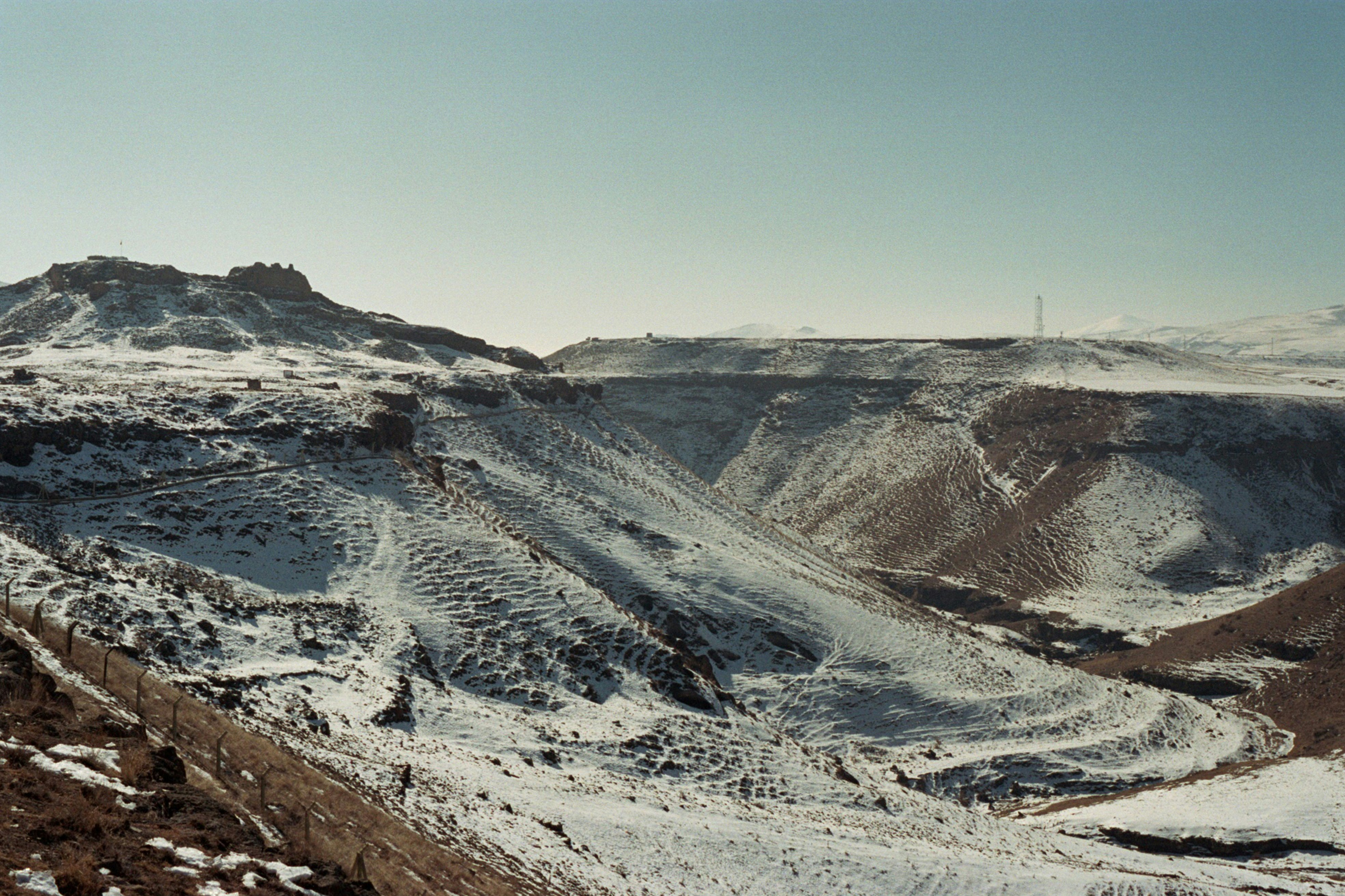 Snow-covered mountains and valleys under a clear sky.