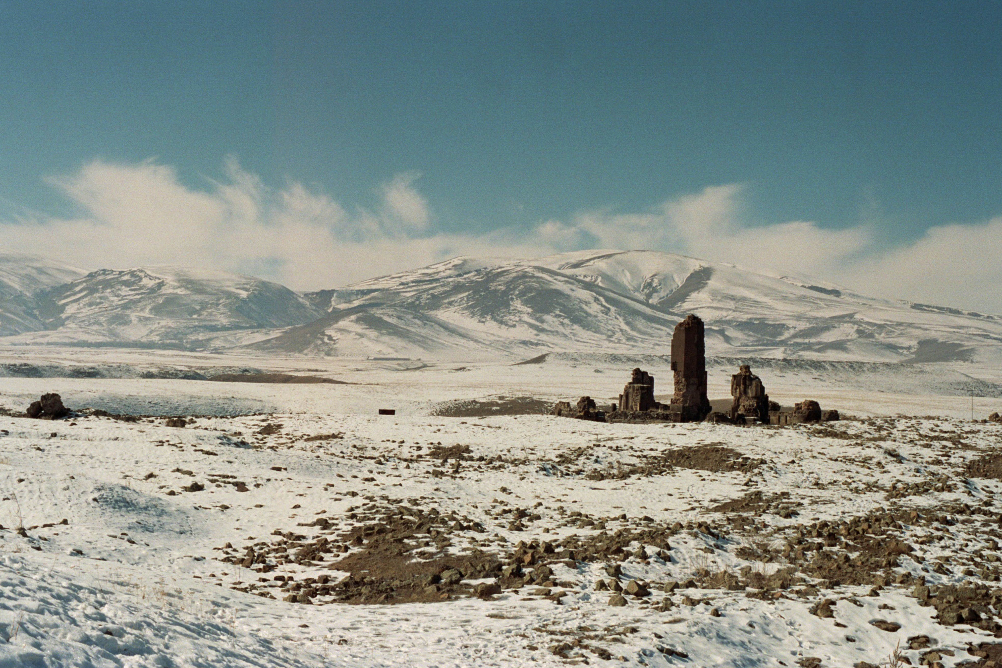 Snowy landscape with stone ruins and mountains.