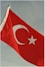 The turkish flag waves against a cloudy sky.
