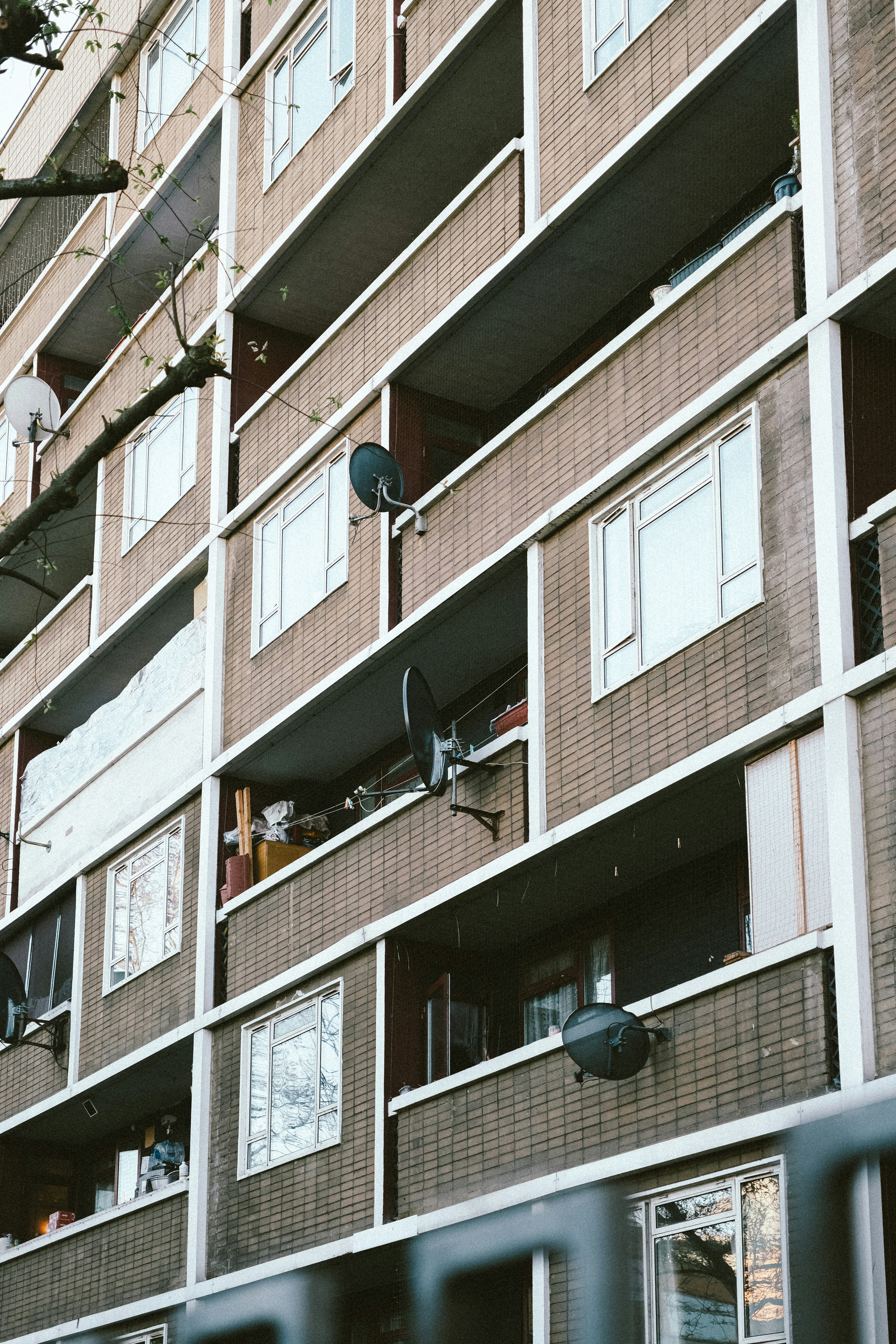 Apartment building with multiple balconies and satellite dishes.