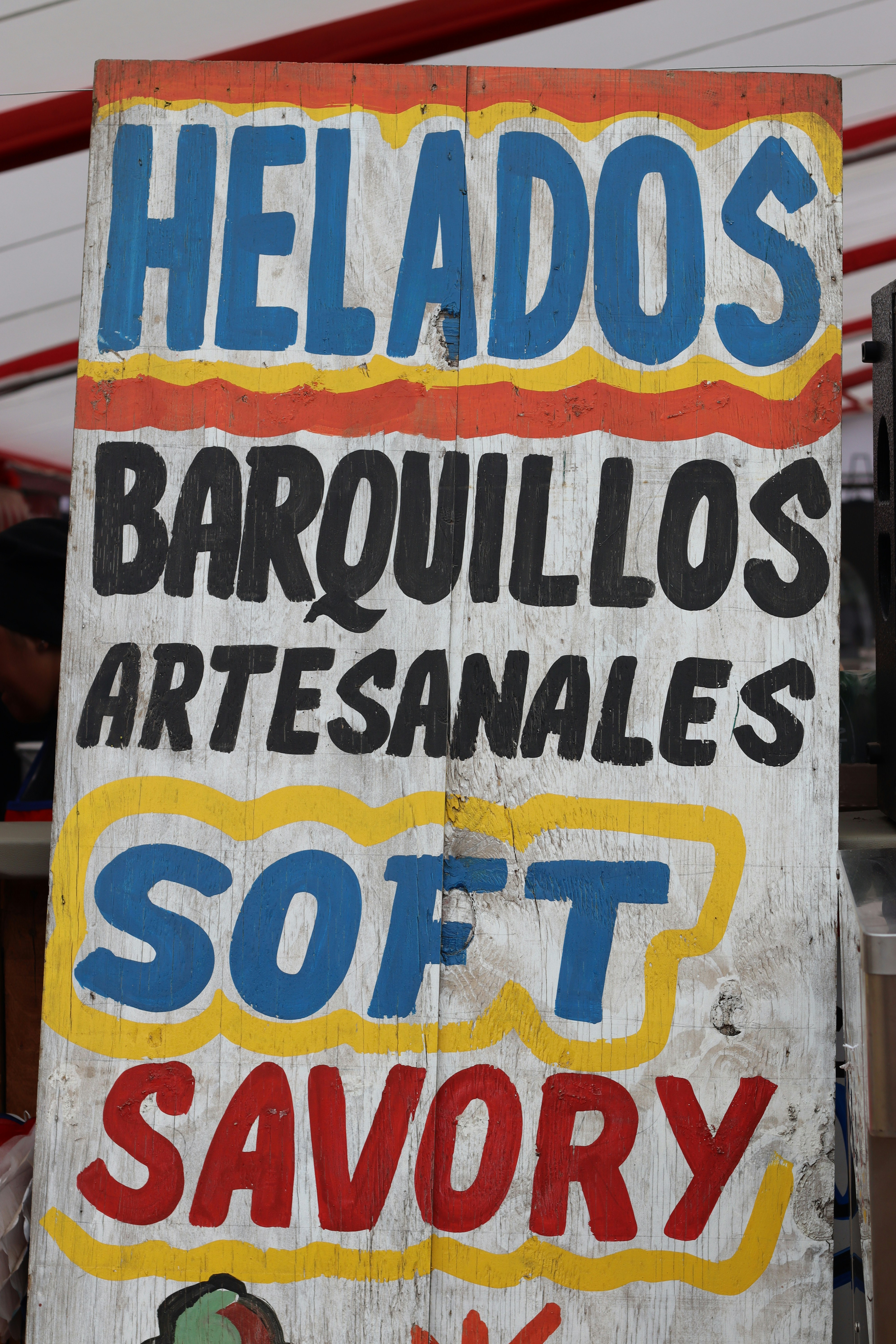 Rustic wooden sign with multi-colored hand-painted text.