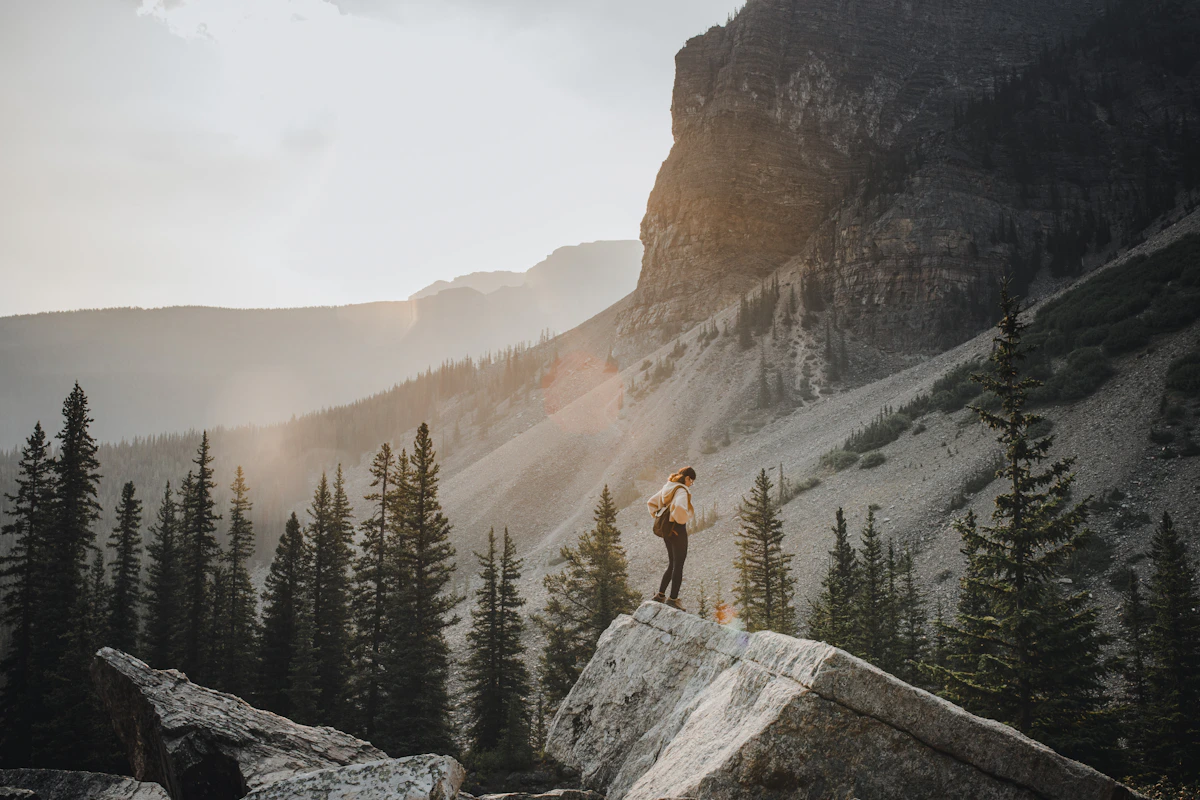 Illustrative editorial scene of a person looking across a mountain landscape at sunset.