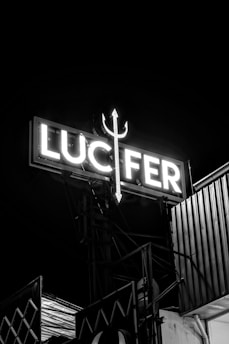 A neon sign says lucifer with a trident.
