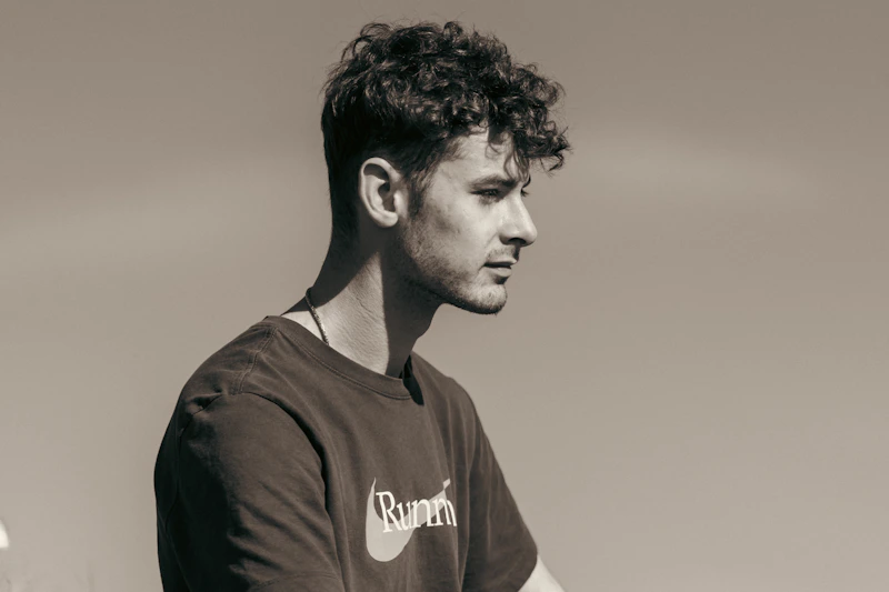 young gay man with curly hair looking away