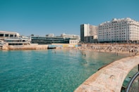 Beach full of people, with buildings in the background.