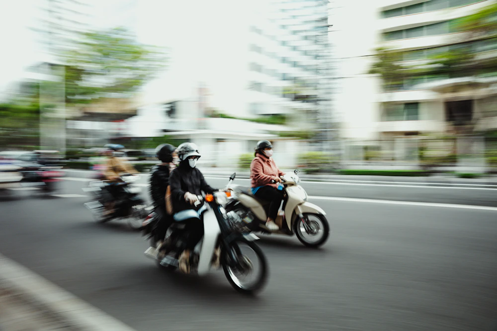 Two helmeted riders travelling by scooter