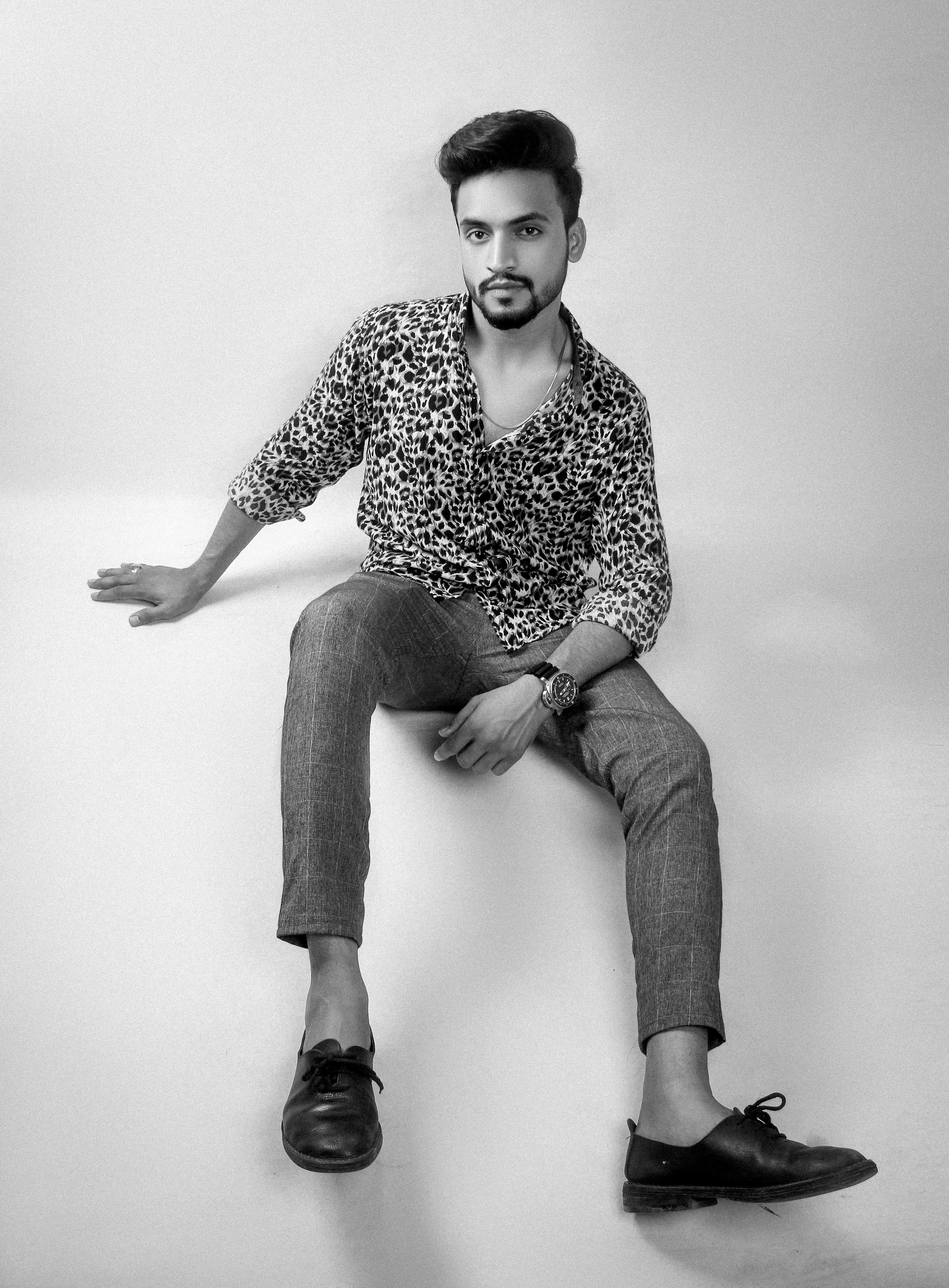 A man poses, sitting with a confident gaze.