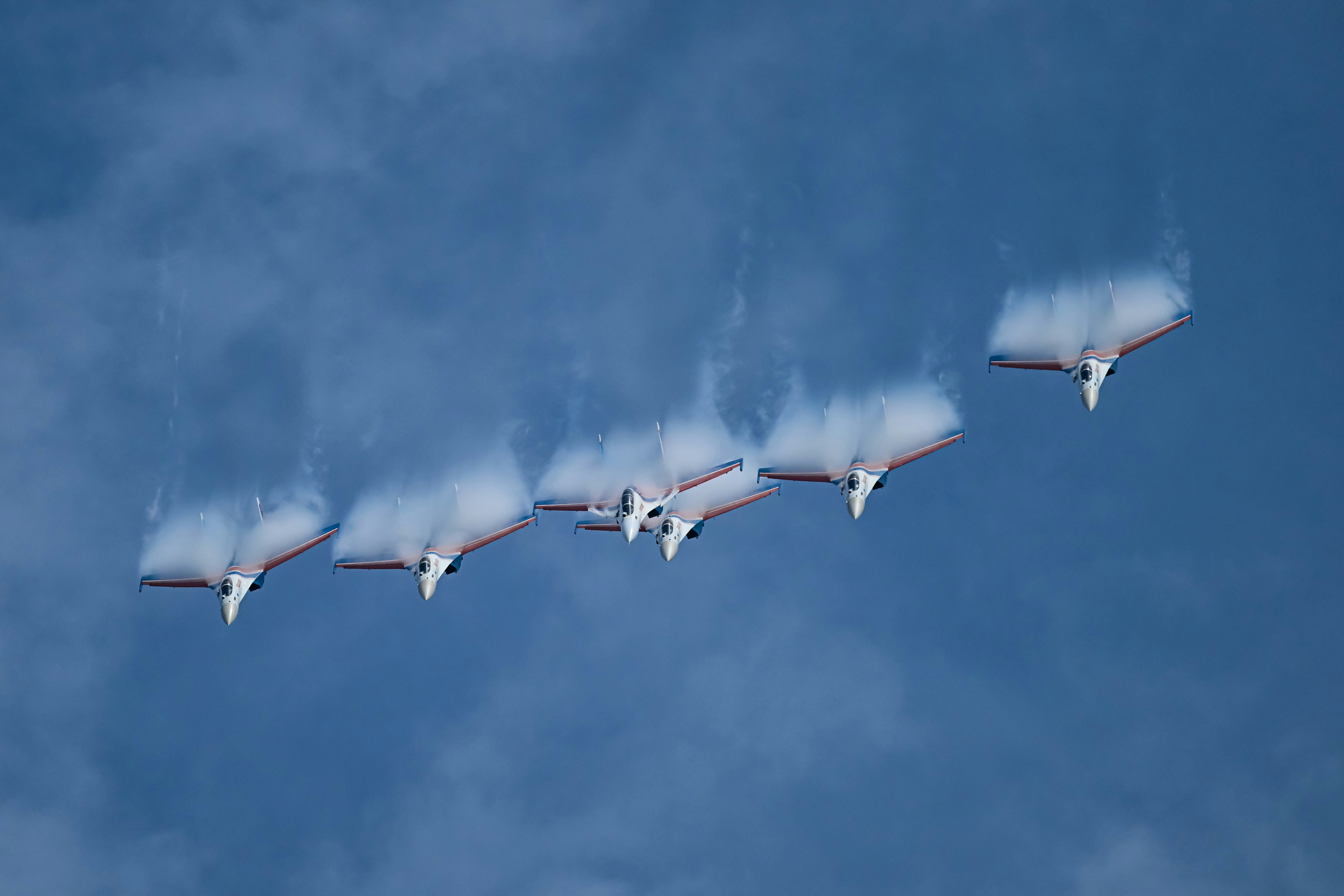 Os jatos realizam manobras aéreas, deixando rastros de vapor.