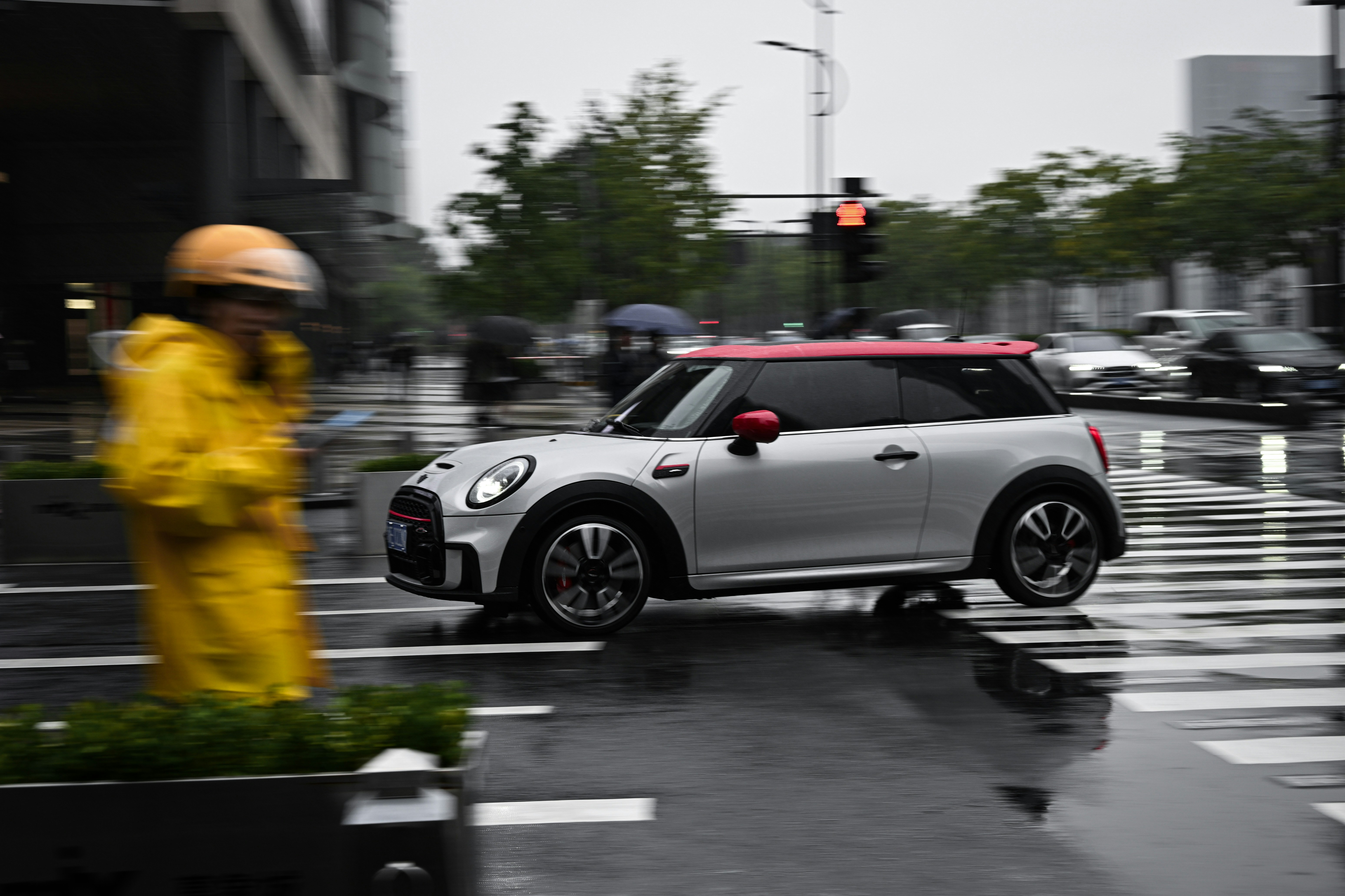 Mini cooper navega em uma rua chuvosa da cidade.