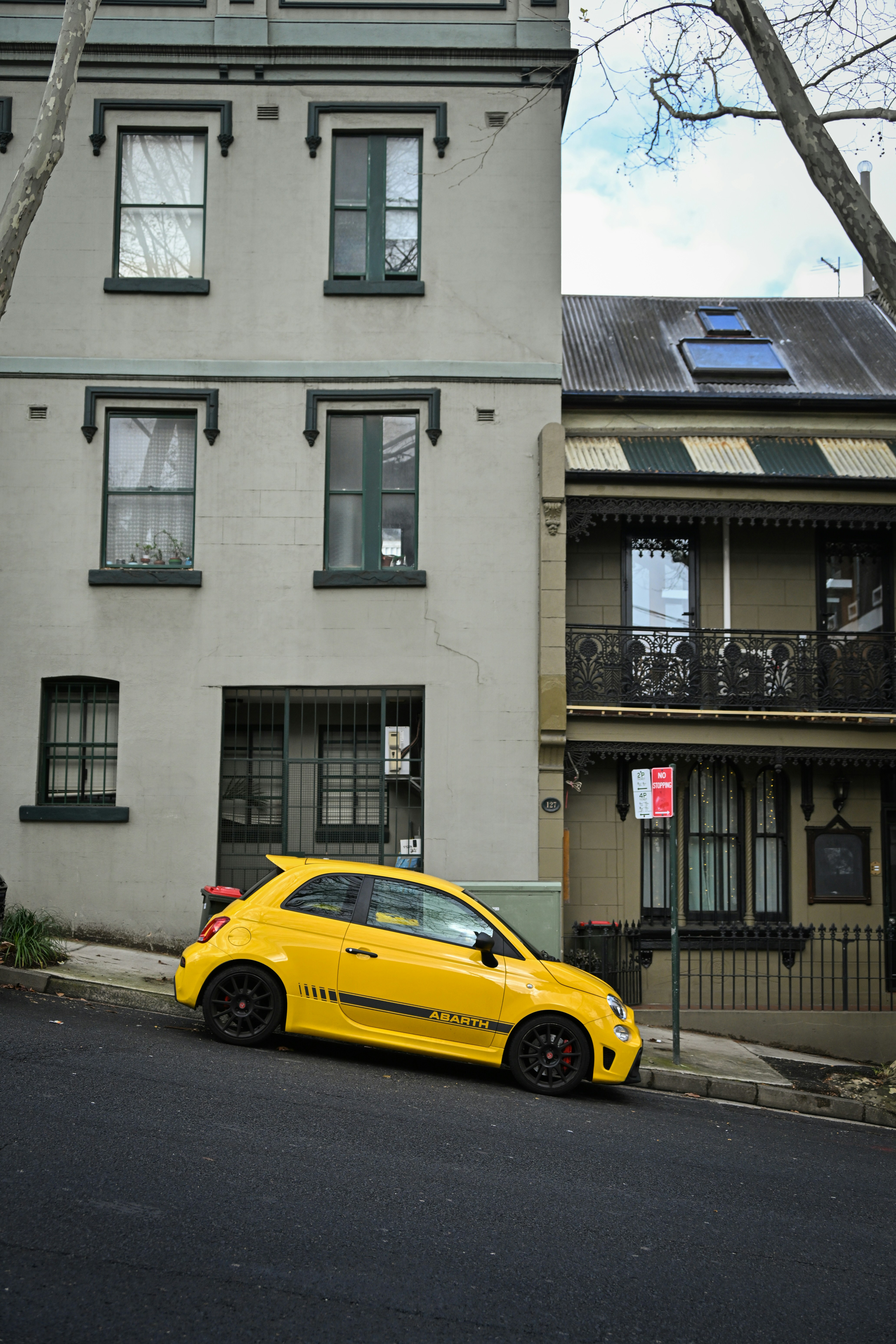 Um carro amarelo estaciona em uma rua inclinada.