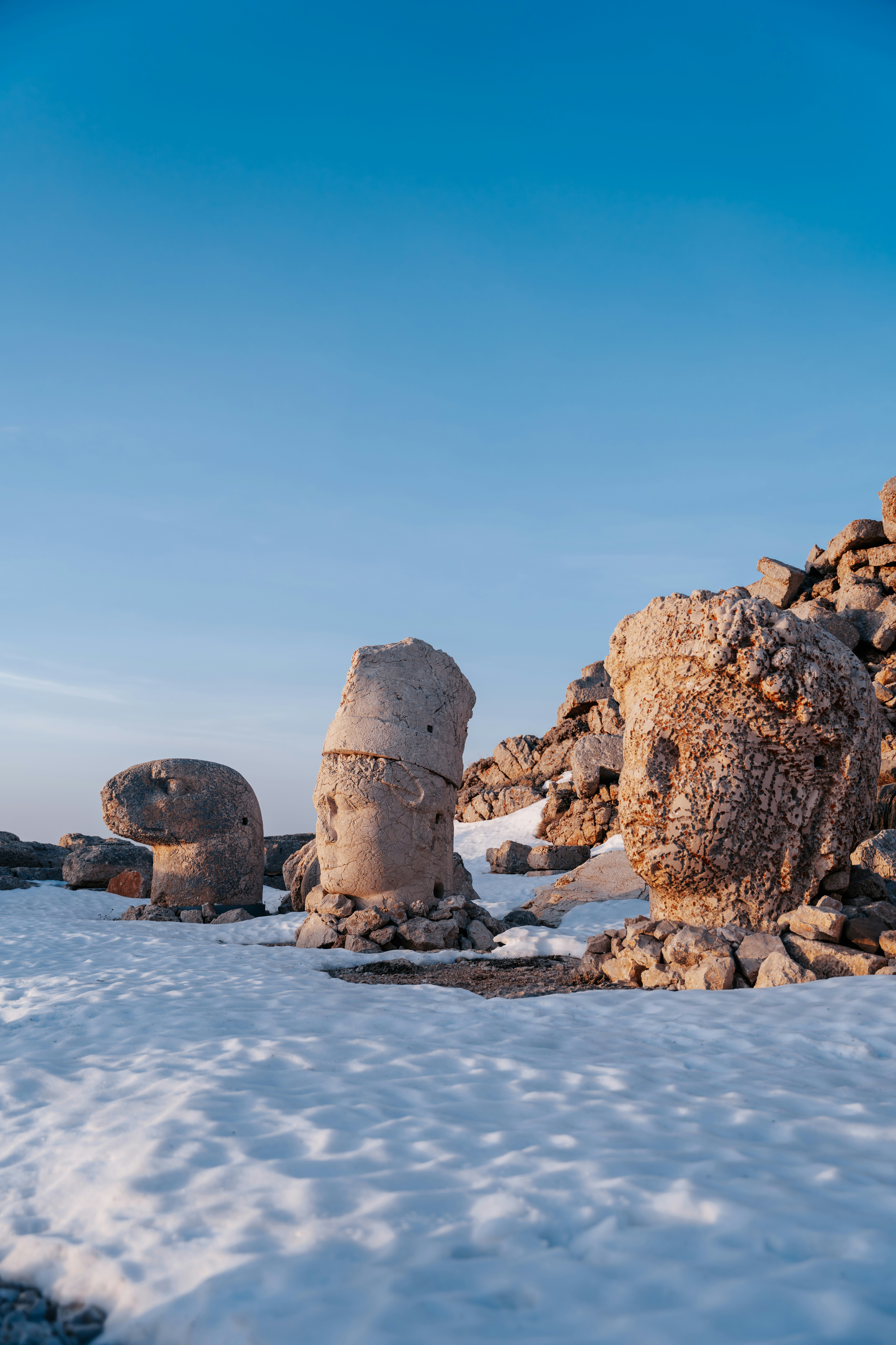 Statues from mount nemrut stand in the snow.