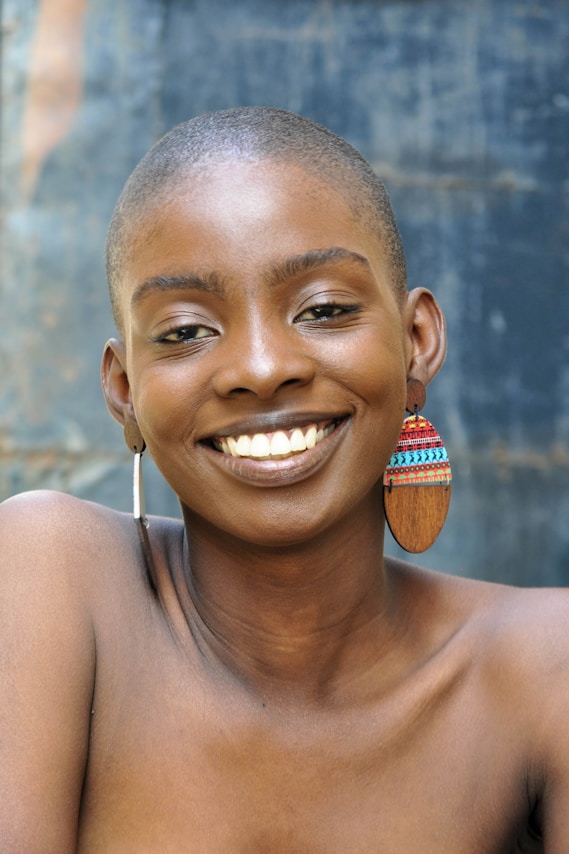 A smiling woman poses with earrings.