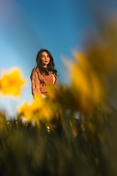 Woman poses among vibrant yellow daffodils.
