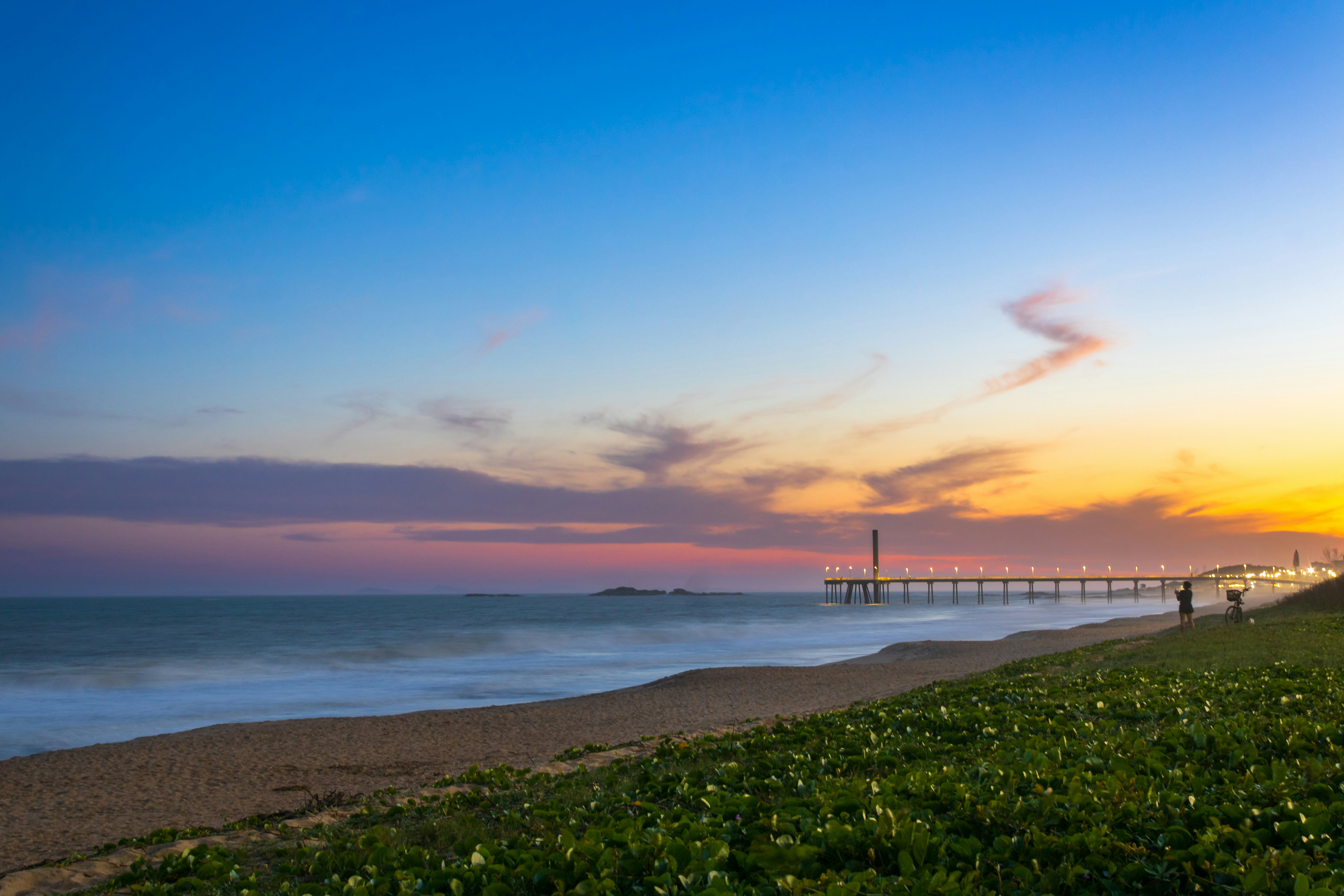 Sunset over the beach with a long pier.