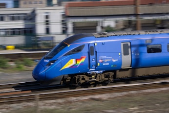 A blue train speeds along the tracks.