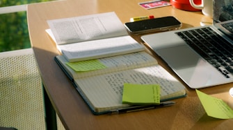 Notebook and laptop sit on a work desk.