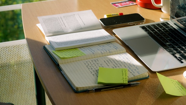 Notebook and laptop sit on a work desk.