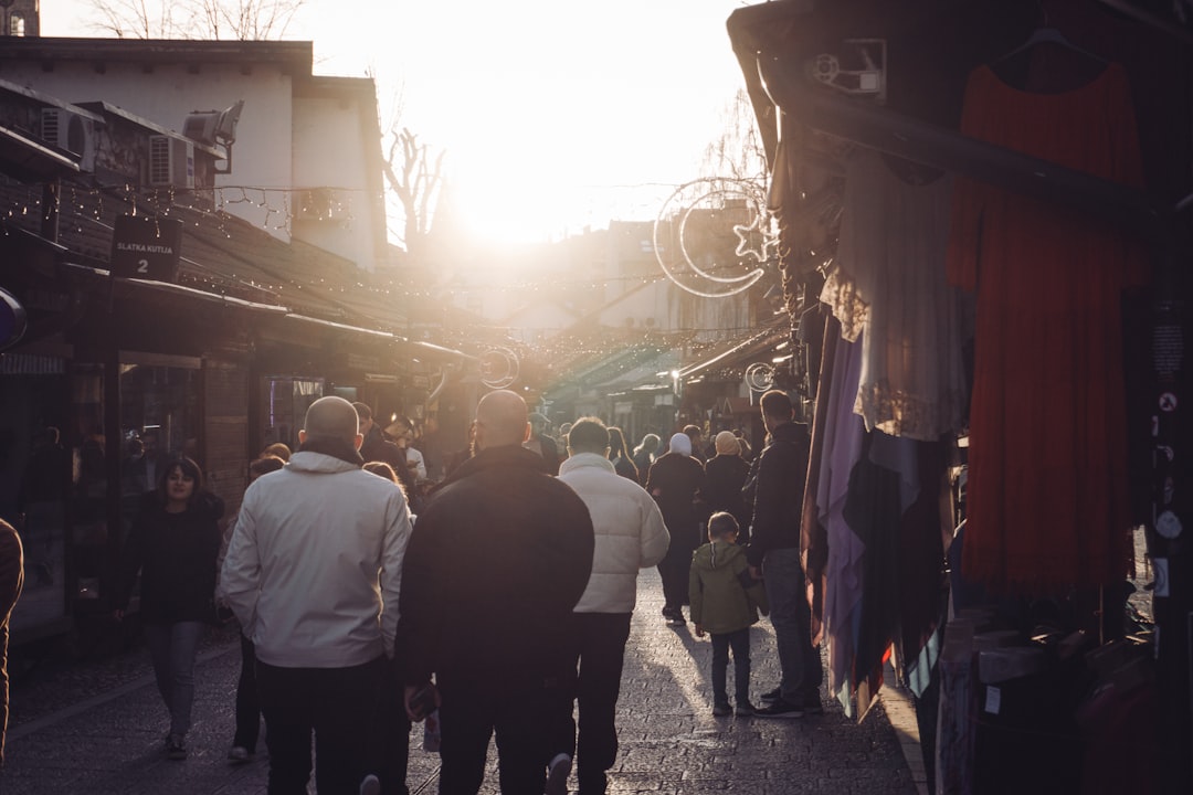 People walk in a sunlit, crowded marketplace.,