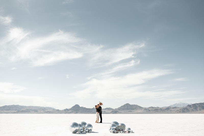 A couple embraces in a vast, open landscape.