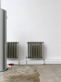 Two radiators stand against a white wall.