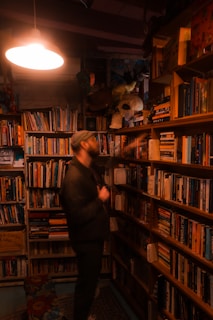 Man browses books in a cozy, dimly lit bookstore.