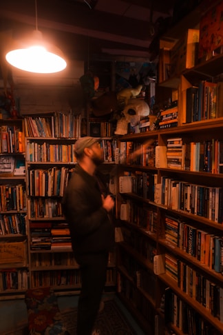 Man browses books in a cozy, dimly lit bookstore.