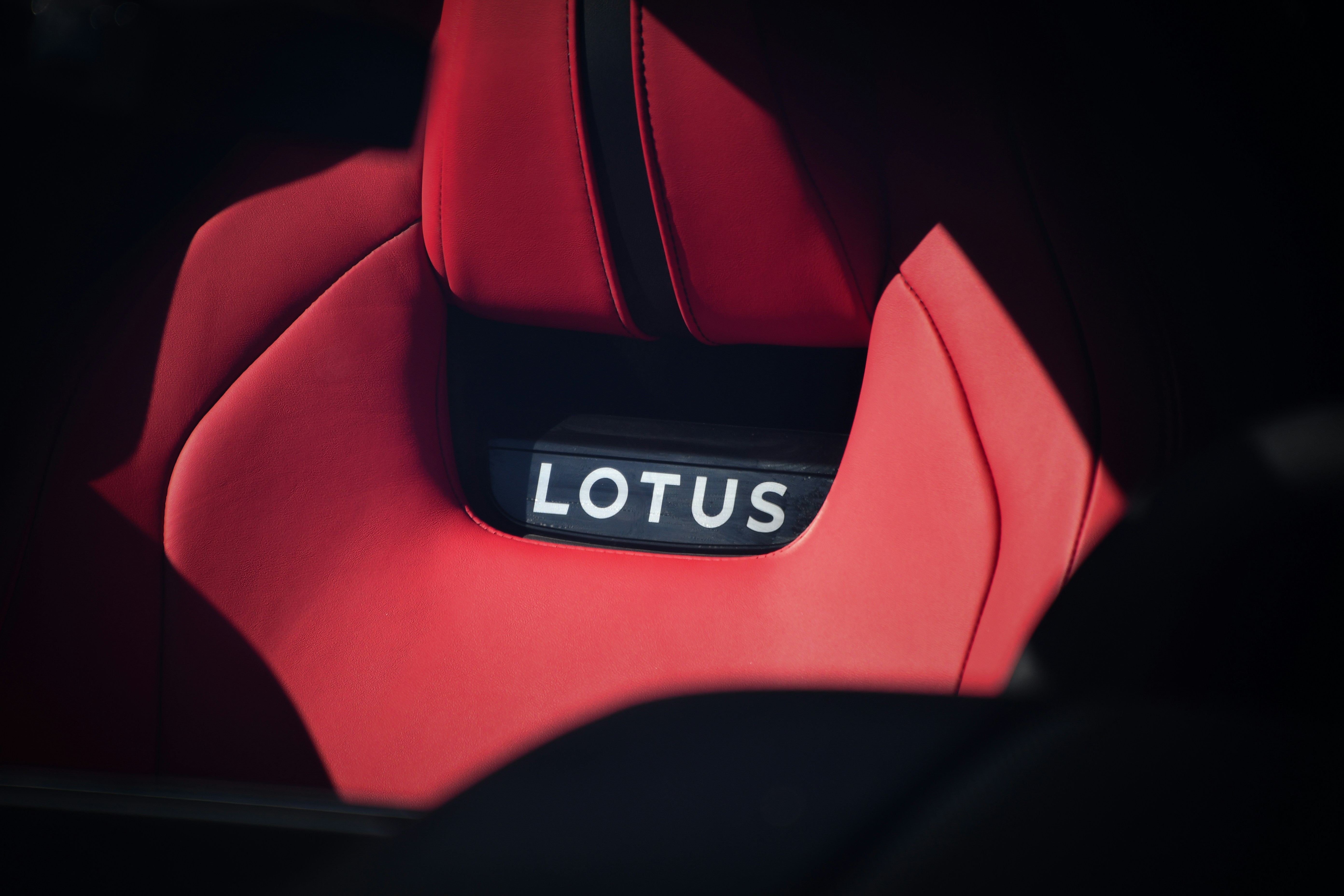 A red car seat with the lotus logo.