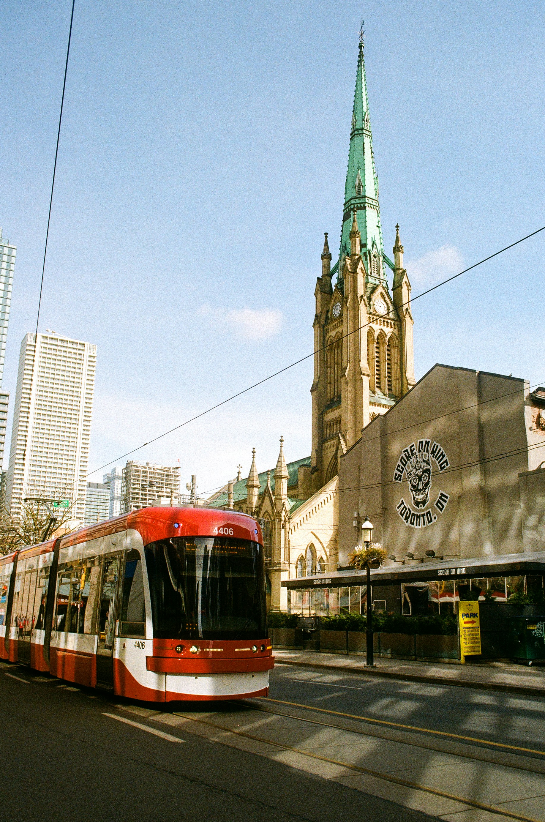 A red streetcar travels past a church.