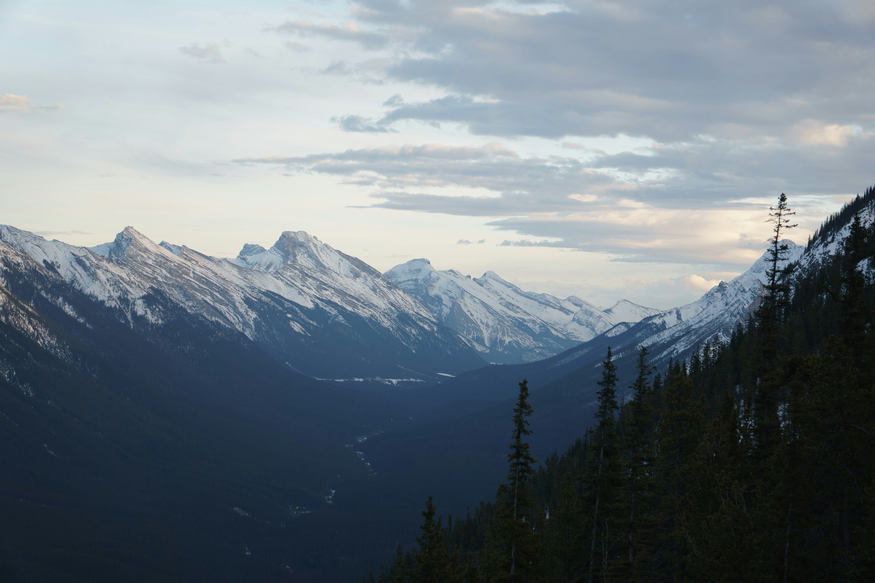 Snowy mountains and valley under a cloudy sky.