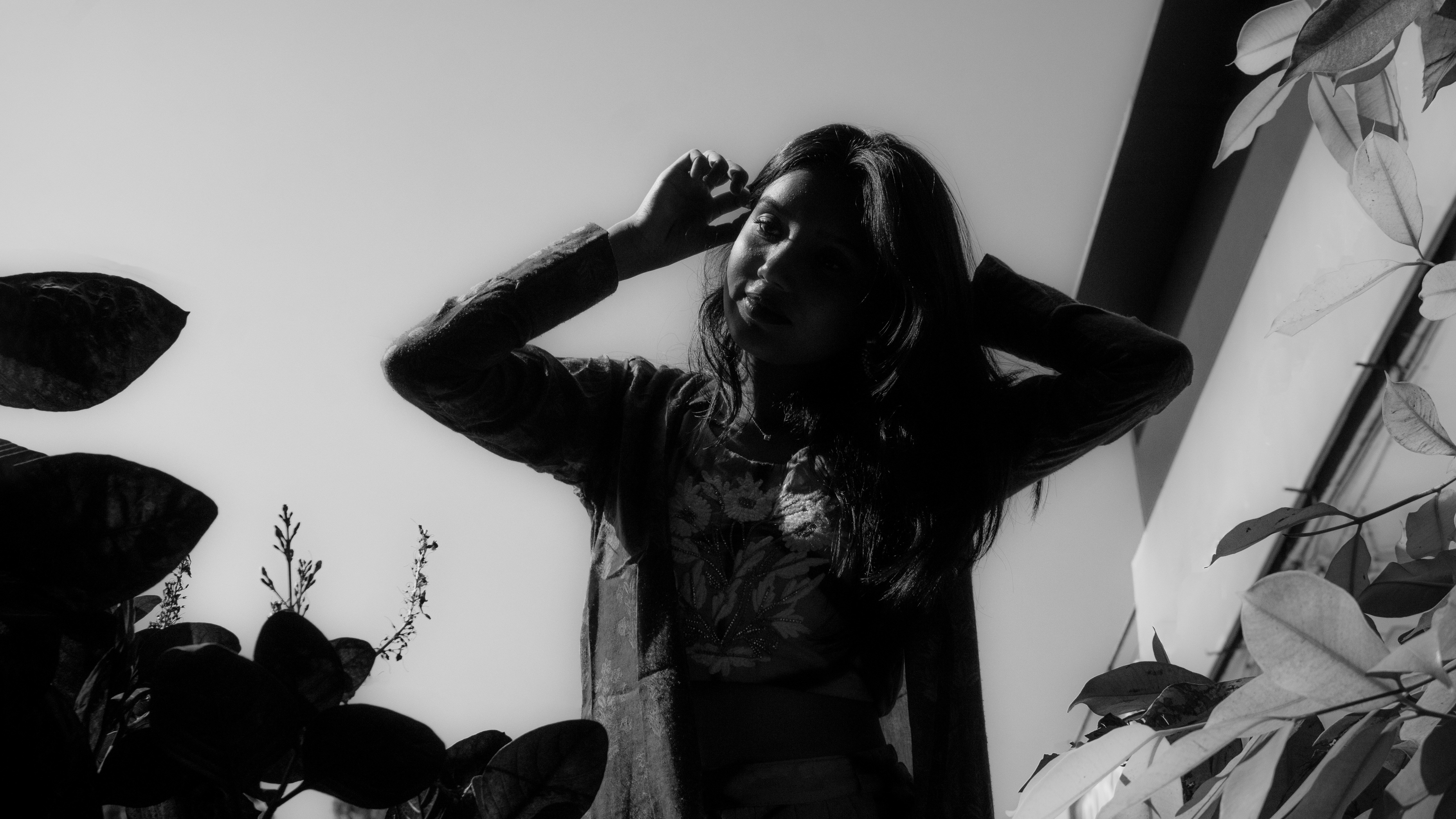 Woman stretches by a window, shot in black and white.