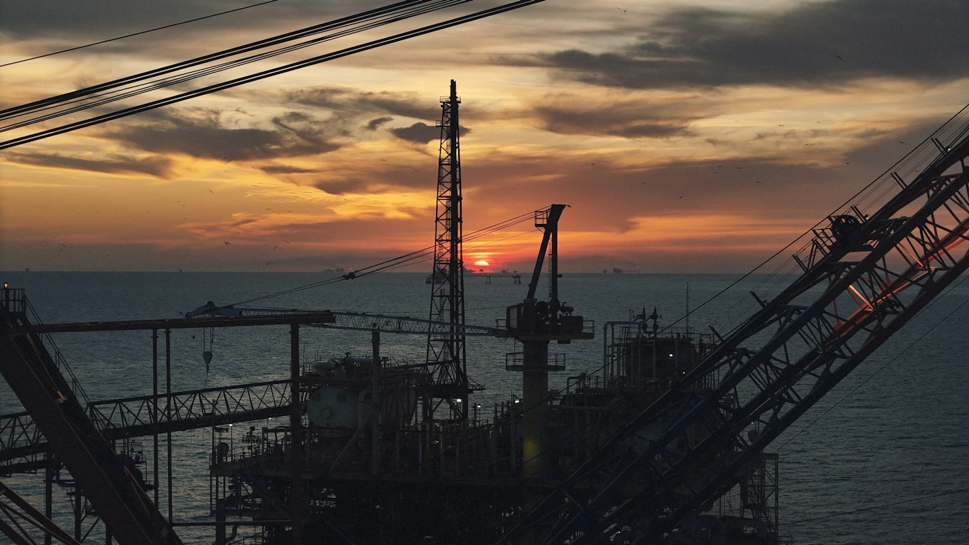 Offshore oil platform silhouetted against a dramatic dusk sky representing wrongful death at sea cases