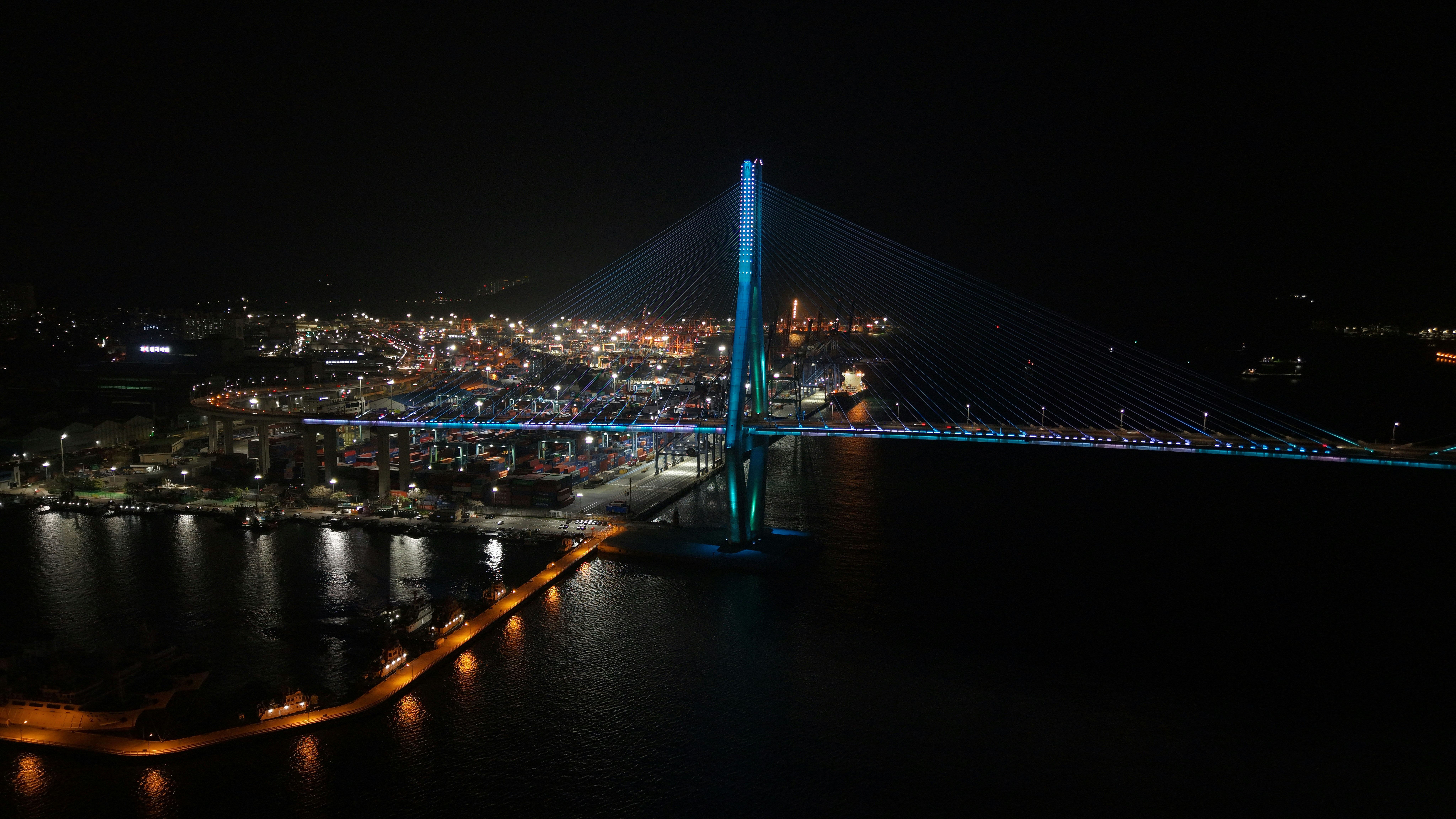 A lit-up bridge over water at night.