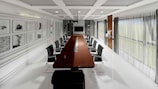 Modern, minimalist boardroom with long table and chairs.