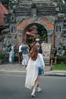 Woman walks toward an ornate, traditional balinese gate.