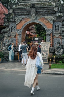 Woman walks toward an ornate, traditional balinese gate.