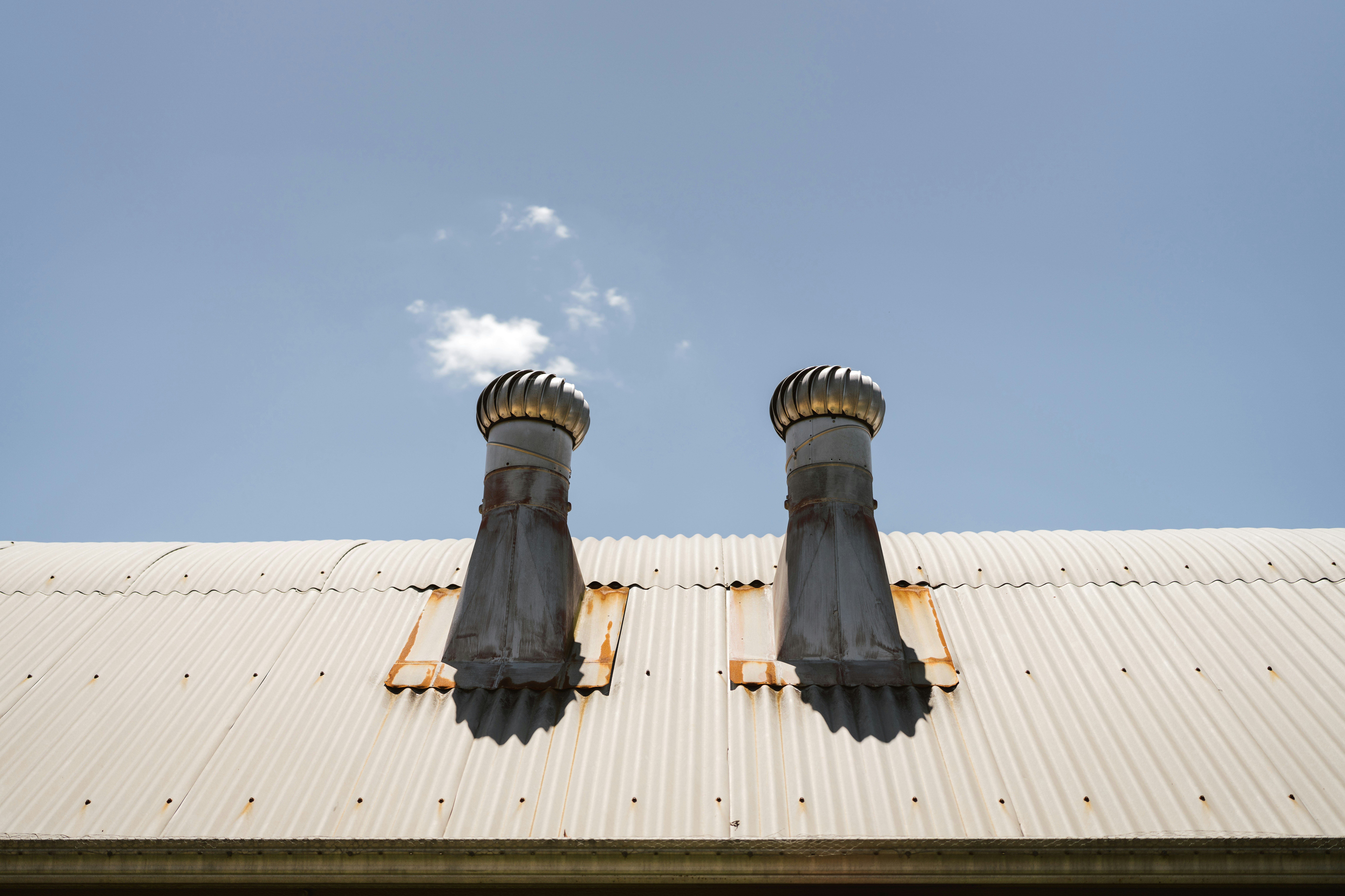 Two chimneys with smoke against a blue sky.