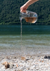 Water is poured from a jug onto the beach.